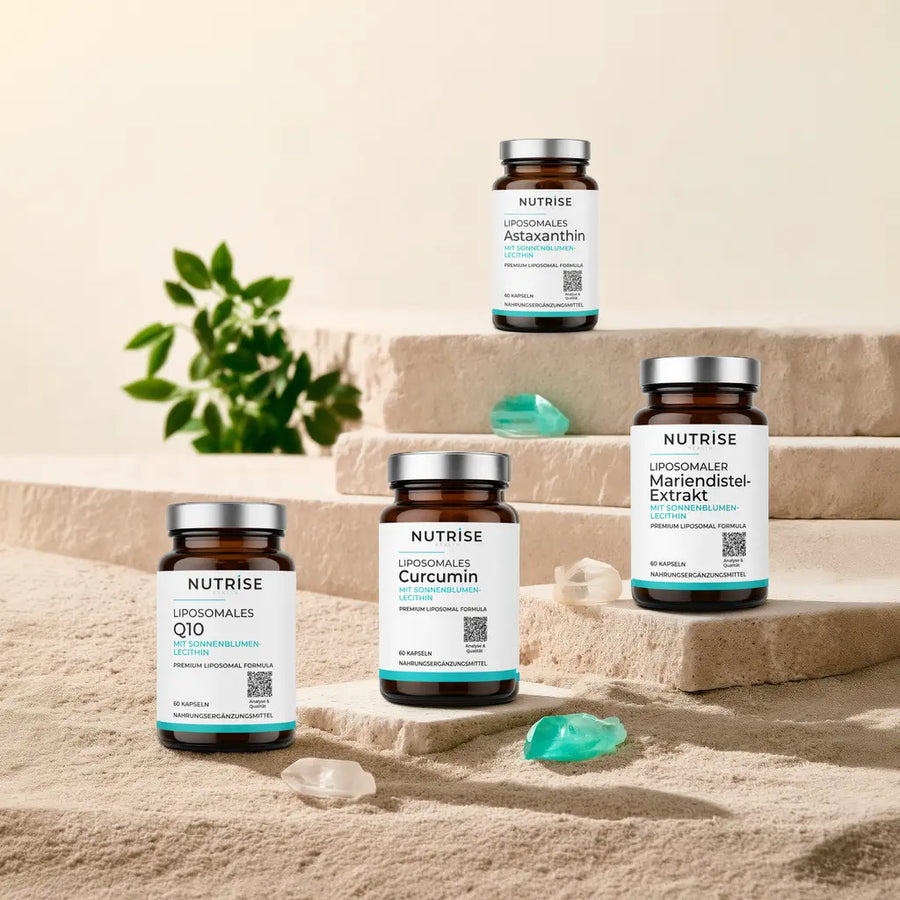 Vier liposomale Nutrise Health Produkte – Astaxanthin, Curcumin, Q10 und Mariendistel-Extrakt – auf Kalkstein mit Sand und türkisen Kristallen.